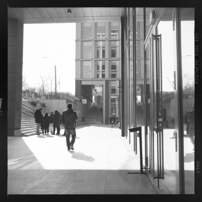 In lumina reprezinta un barbat mergand spre lumina intr-un pasaj urban modern, fotografie artistica alb-negru.