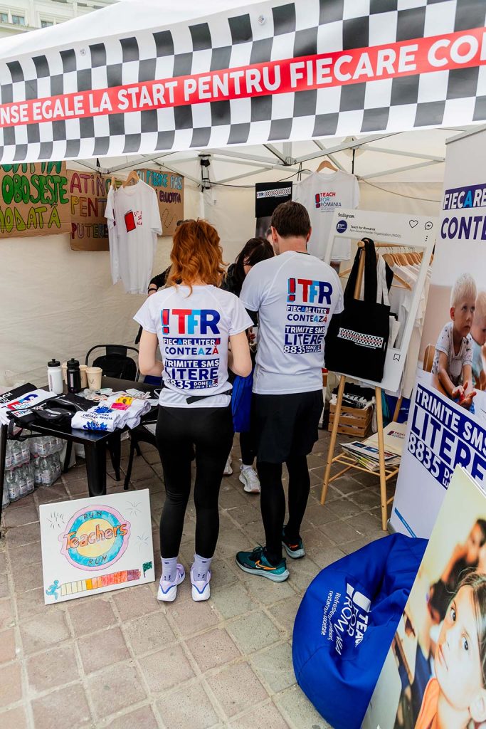 Standul Teach For Romania la OMV Petrom Bucharest Half Marathon 2026 cu voluntari in tricouri albe si materiale de promovare a educatiei.