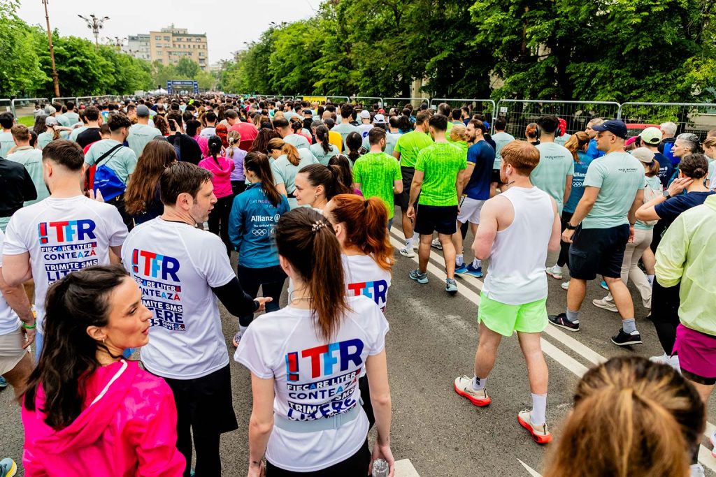 Echipa Teach For Romania in tricouri albe cu inscriptii TFR asteptand la startul OMV Petrom Bucharest Half Marathon 2026 inconjurata de alti alergatori.