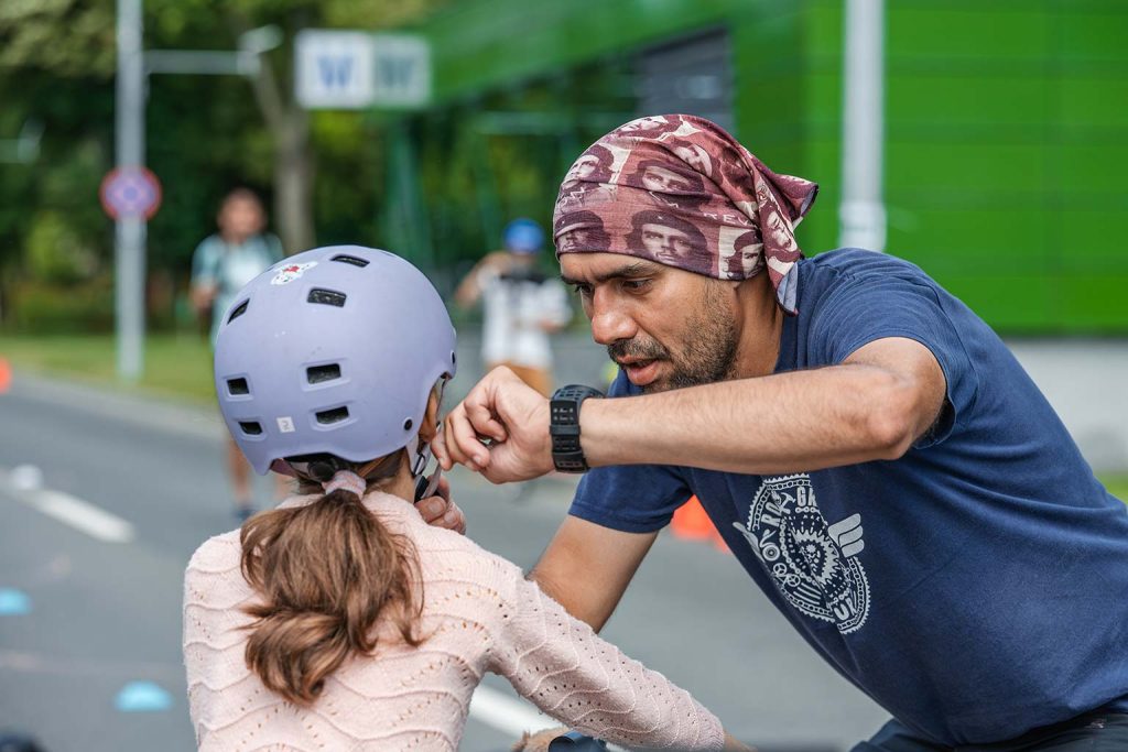 Popa Bogdan, antrenor verificand casca de protectie a unei fetite inainte de a lua startul intr-un trase la Parada micilor Ciclisti