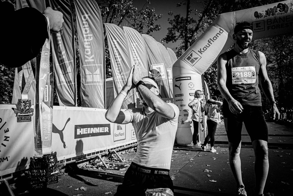 Alergator ingenuncheat in semn de multumire la finishul Baneasa Forest Run 2025, medalii in prim-plan, fotografie alb-negru