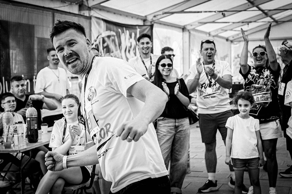 Sportiv bucurandu-se pentru victorie la festivitatea de premiere, inconjurat de sustinatori care aplauda.