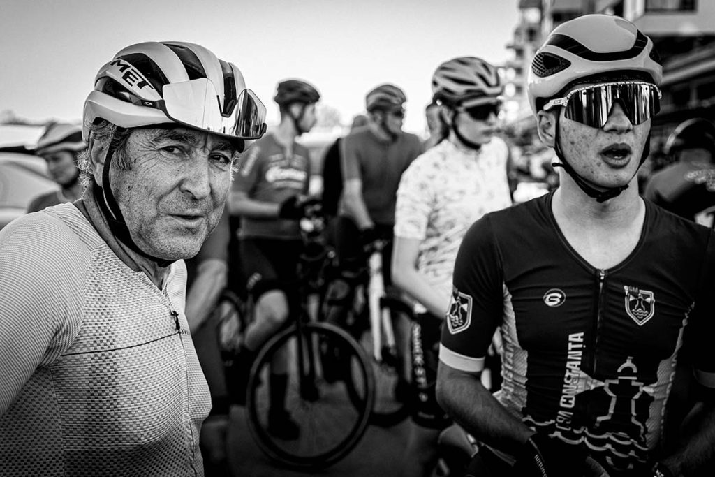 Fotografie sportiva ciclism rutier - doi ciclisti, unul mai in varsta si unul tanar, echipati complet, la startul Turului Ciclist CELCO, fotografie alb-negru.