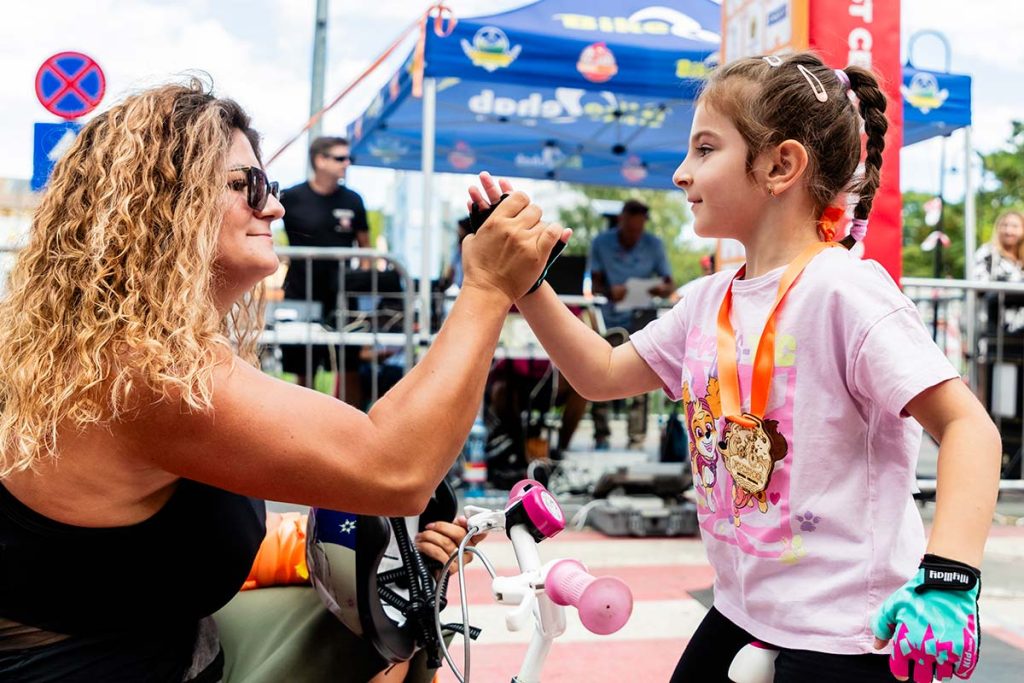 Fotografie sportiva la concurs de copii surprinzand o tanara participanta pe bicicleta traversand linia de finish la Turul Ciclist CELCO.