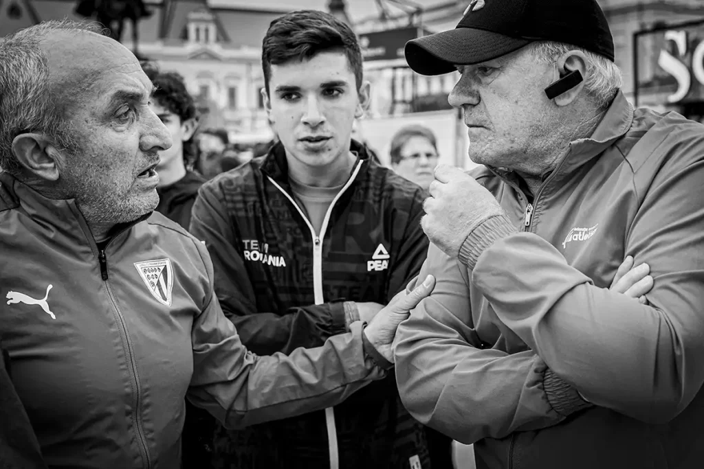Doi antrenori discutand cu un sportiv in timpul festivitatii de premiere la Oradea Run Fest.